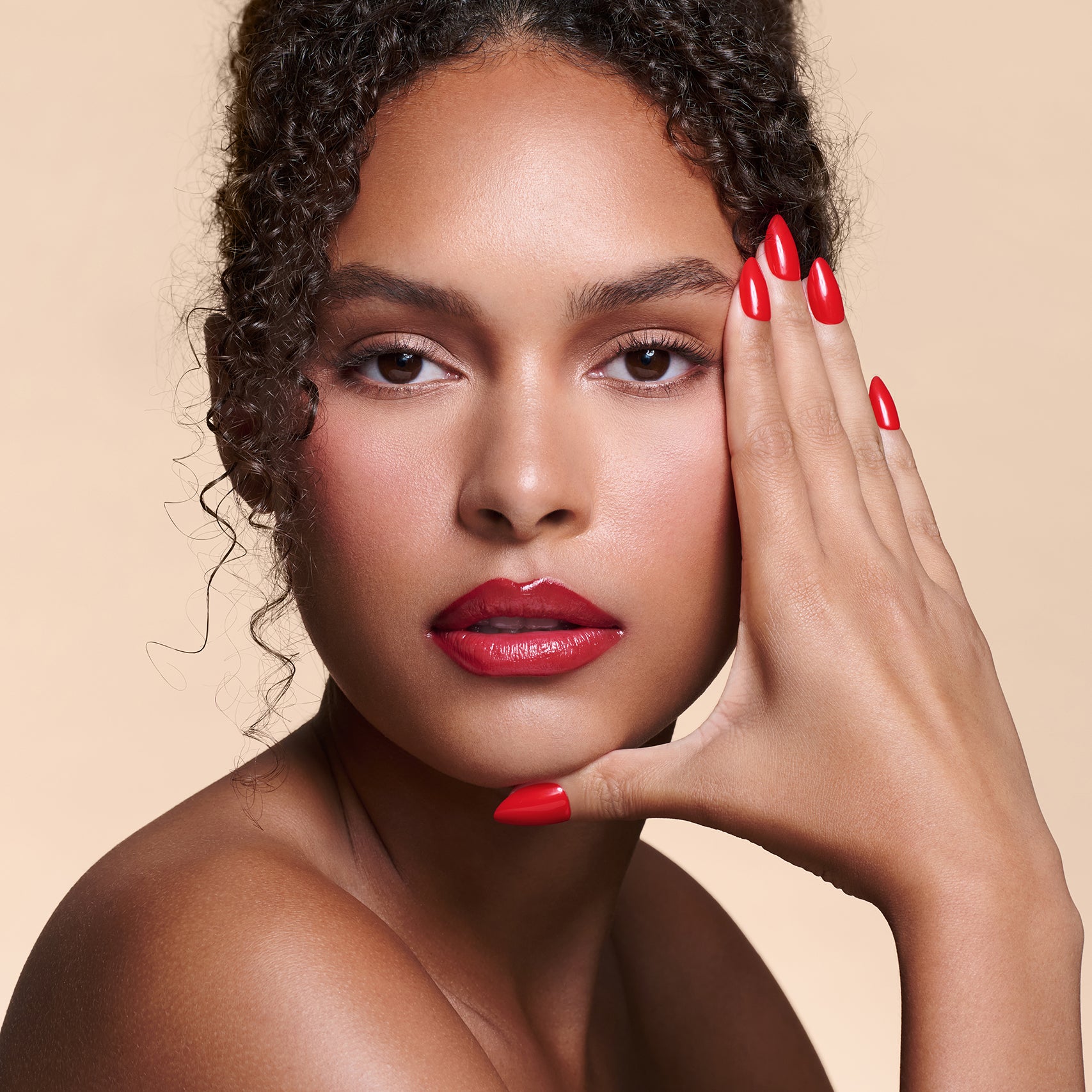 Caught Red Handed red almond press-on nails by Mani Muse, worn by a model (beauty shot).