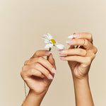 All Damn Daisy nude with daisy accents press-on nails by Mani Muse, close-up hand shot.
