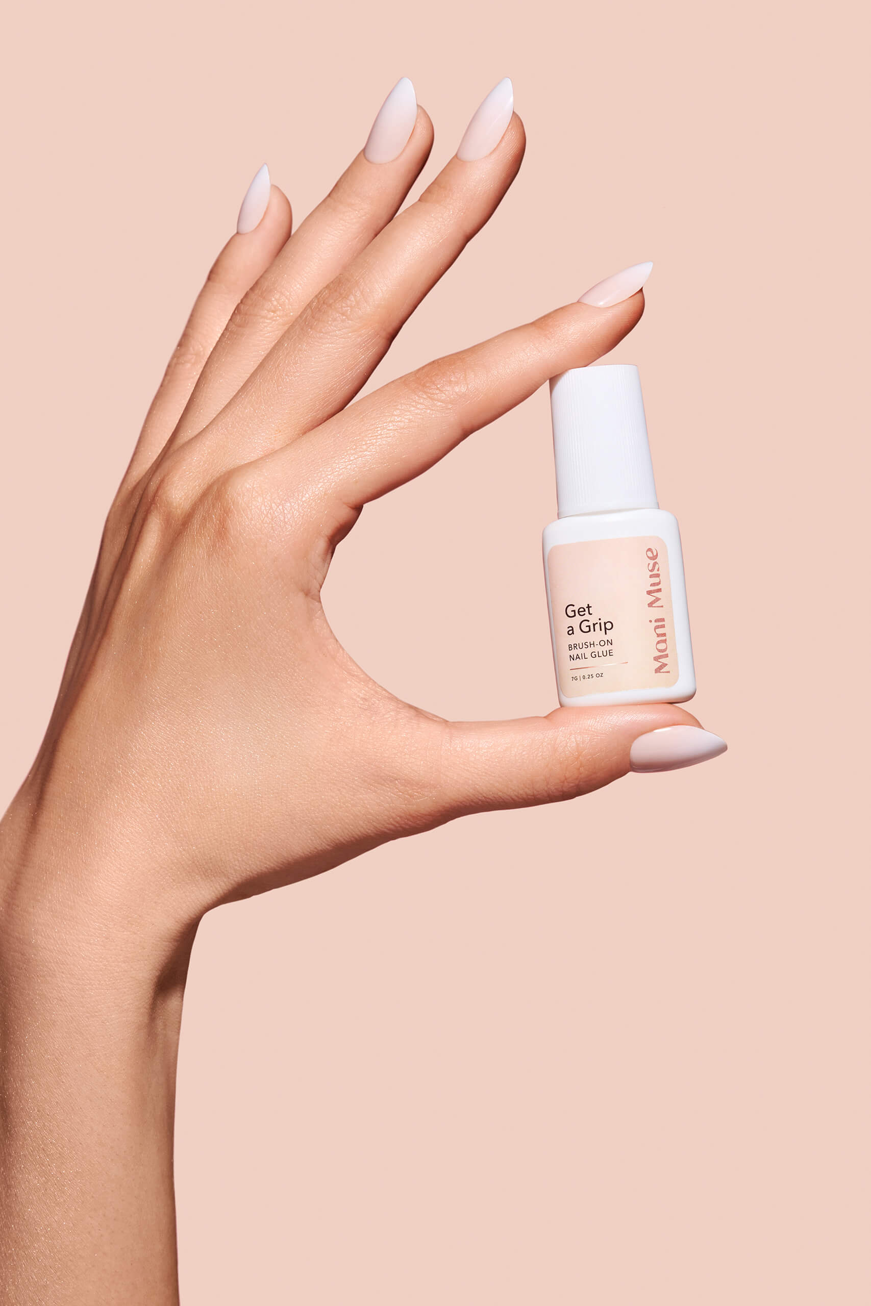 Close-up hand shot of Get a Grip nail glue by Mani Muse. Ultra-strong brush-on adhesive for salon-quality press-on nails at home.