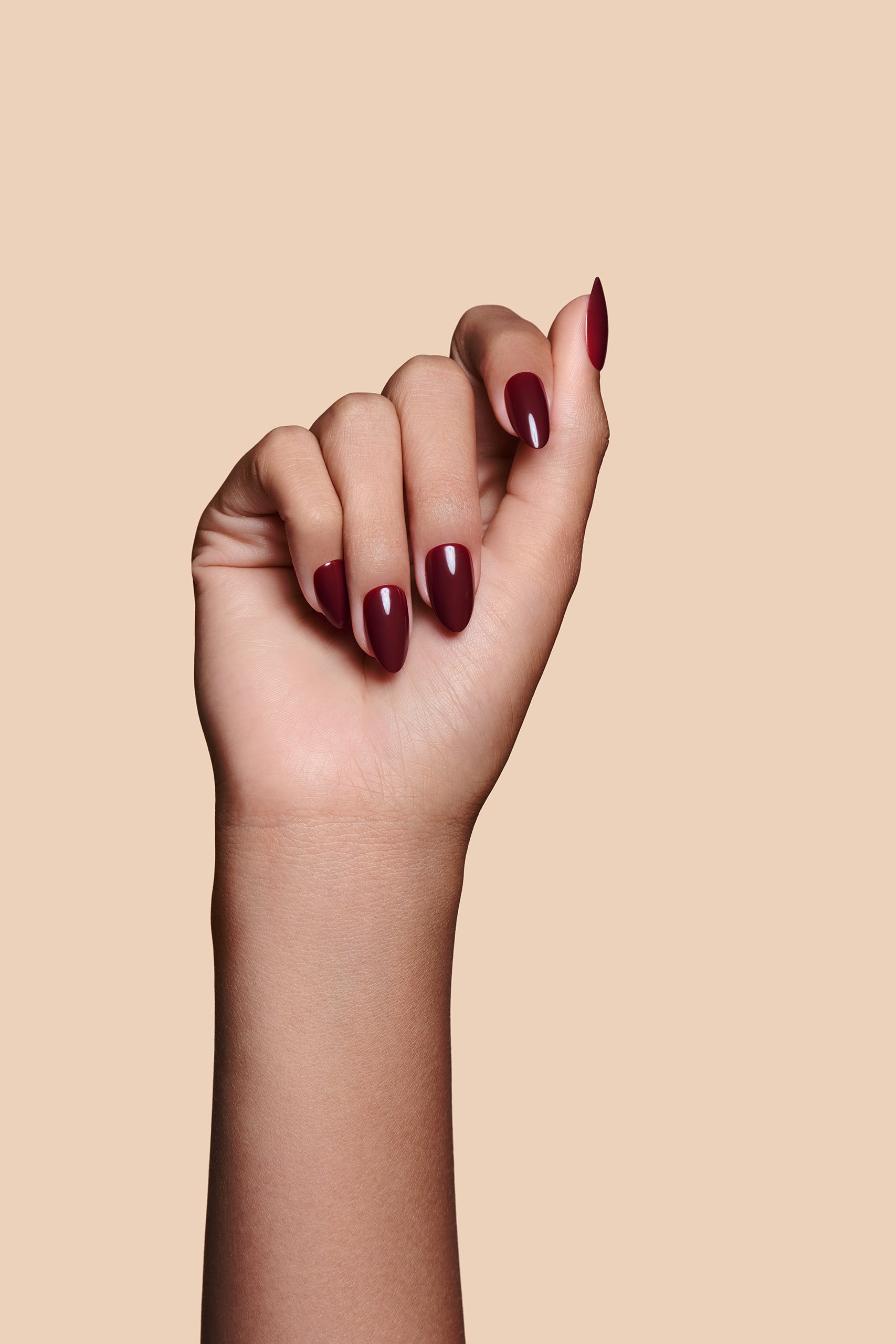 Like a Fine Wino burgundy press-on nails by Mani Muse, close-up hand shot.